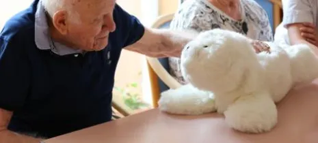 Homme âge qui caresse une peluche 